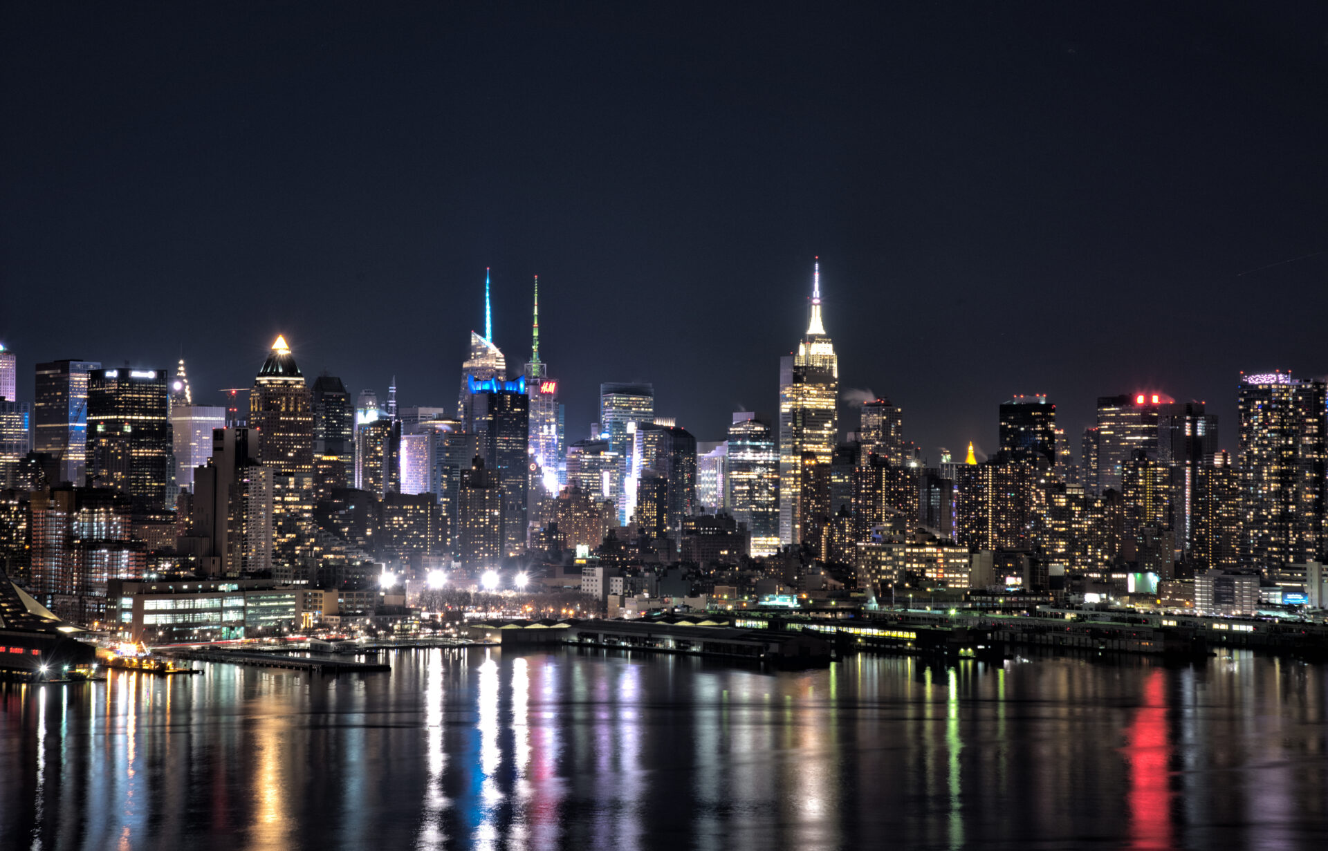 New York city skyline at night with building lights reflected in